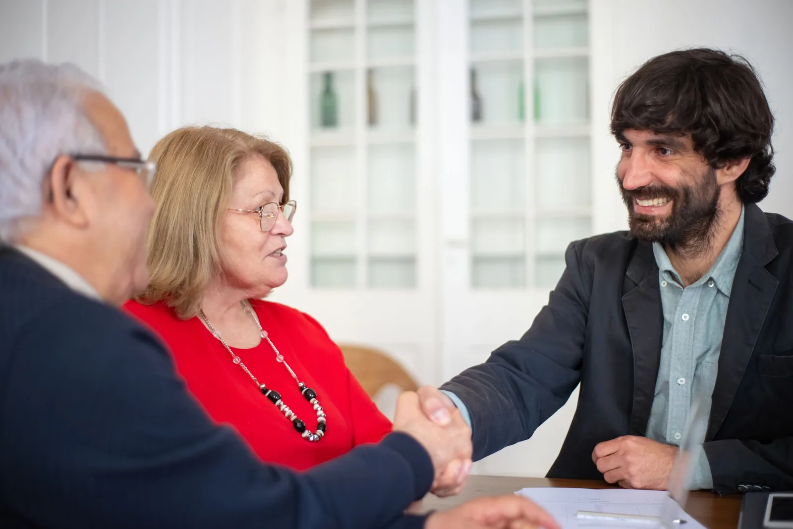 Financial adviser shaking hands with an older couple across a table in Australia. Photo by Kampus Production on Pexels