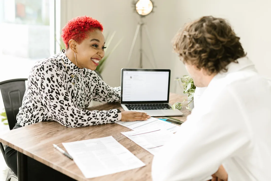 Two people reviewing papers at a table with a laptop. Photo by RDNE Stock project on Pexels