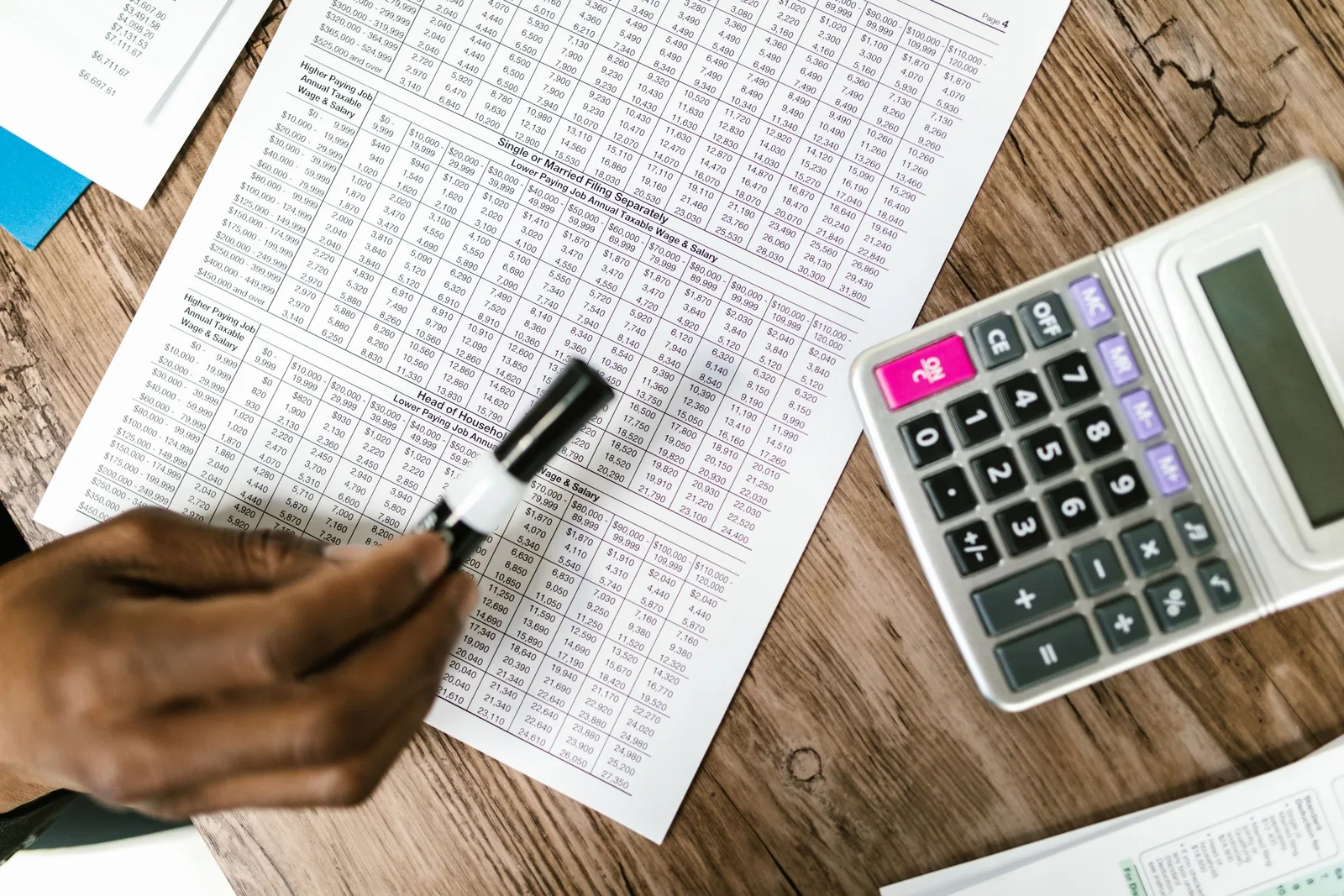 Accountant marking tax forms with a calculator on a wooden desk. Photo by RDNE Stock project on Pexels