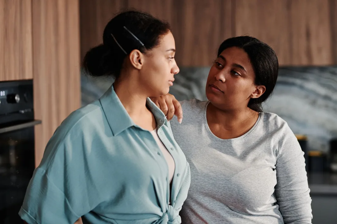 Two women comforting each other in a calm, supportive moment at home. Photo by Tiger Lily on Pexels