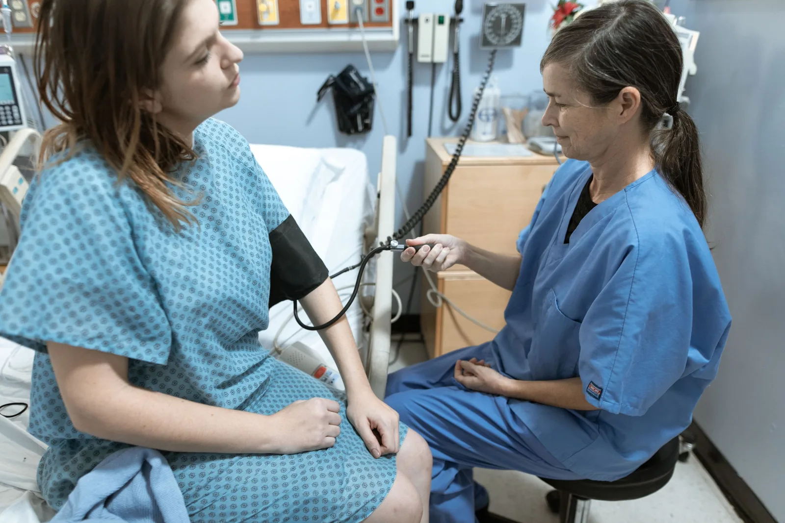 Clinician taking a patient's blood pressure in a bright examination room. Photo by RDNE Stock project on Pexels