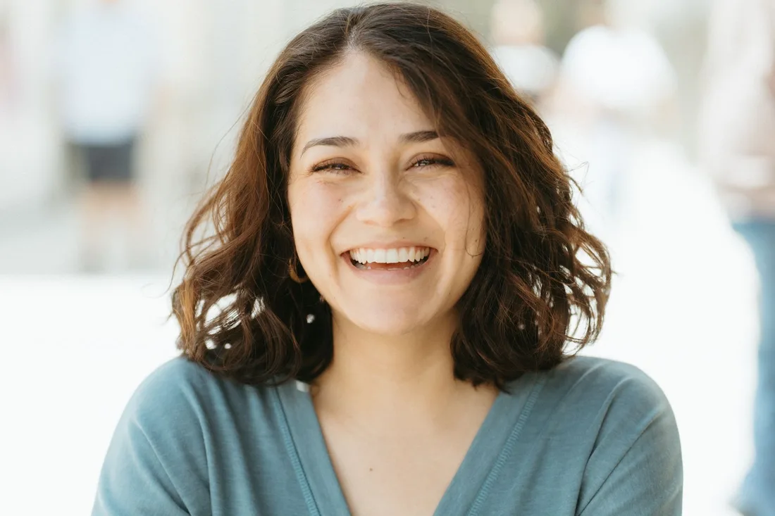 Cheerful woman with a bright natural smile standing in soft daylight in Australia. Photo by Ivan Aguilar on Pexels