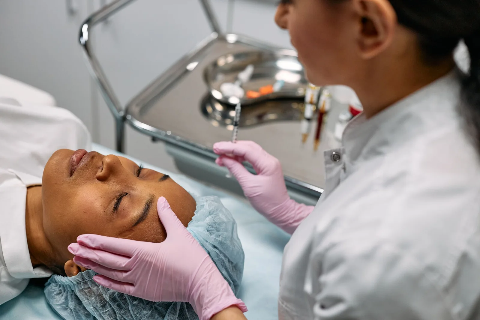 Practitioner in gloves performing an aesthetic facial treatment on a relaxed client lying on a treatment bed. Photo by cottonbro studio on Pexels