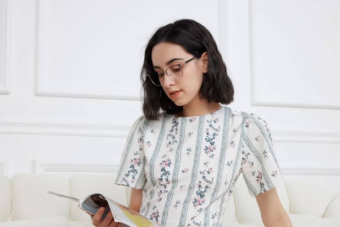 Woman wearing glasses reading a magazine in a bright living room. Photo by GlassesShop GS on Pexels