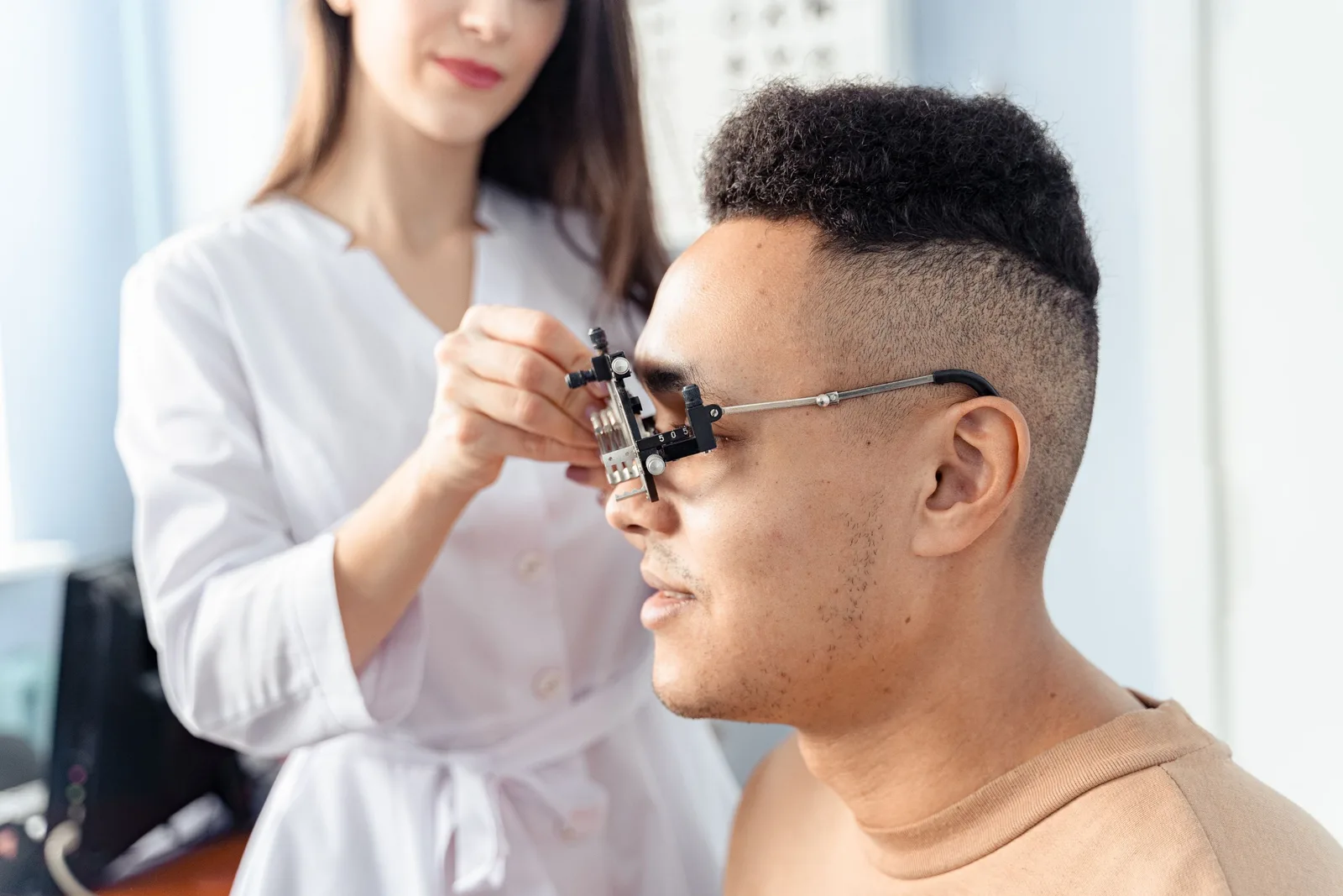 Optometrist fitting a trial frame on a smiling male patient during an eye exam. Photo by Antoni Shkraba on Pexels