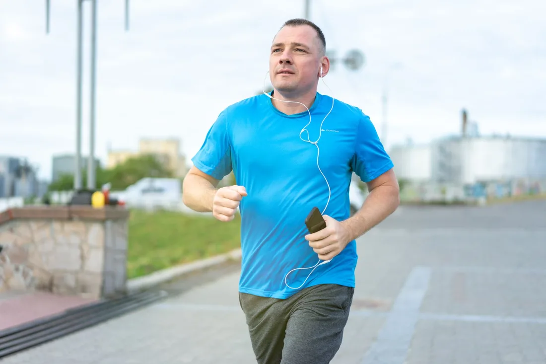 Man in a blue shirt jogging along a paved path in the daylight. Photo by Atlantic Ambience on Pexels
