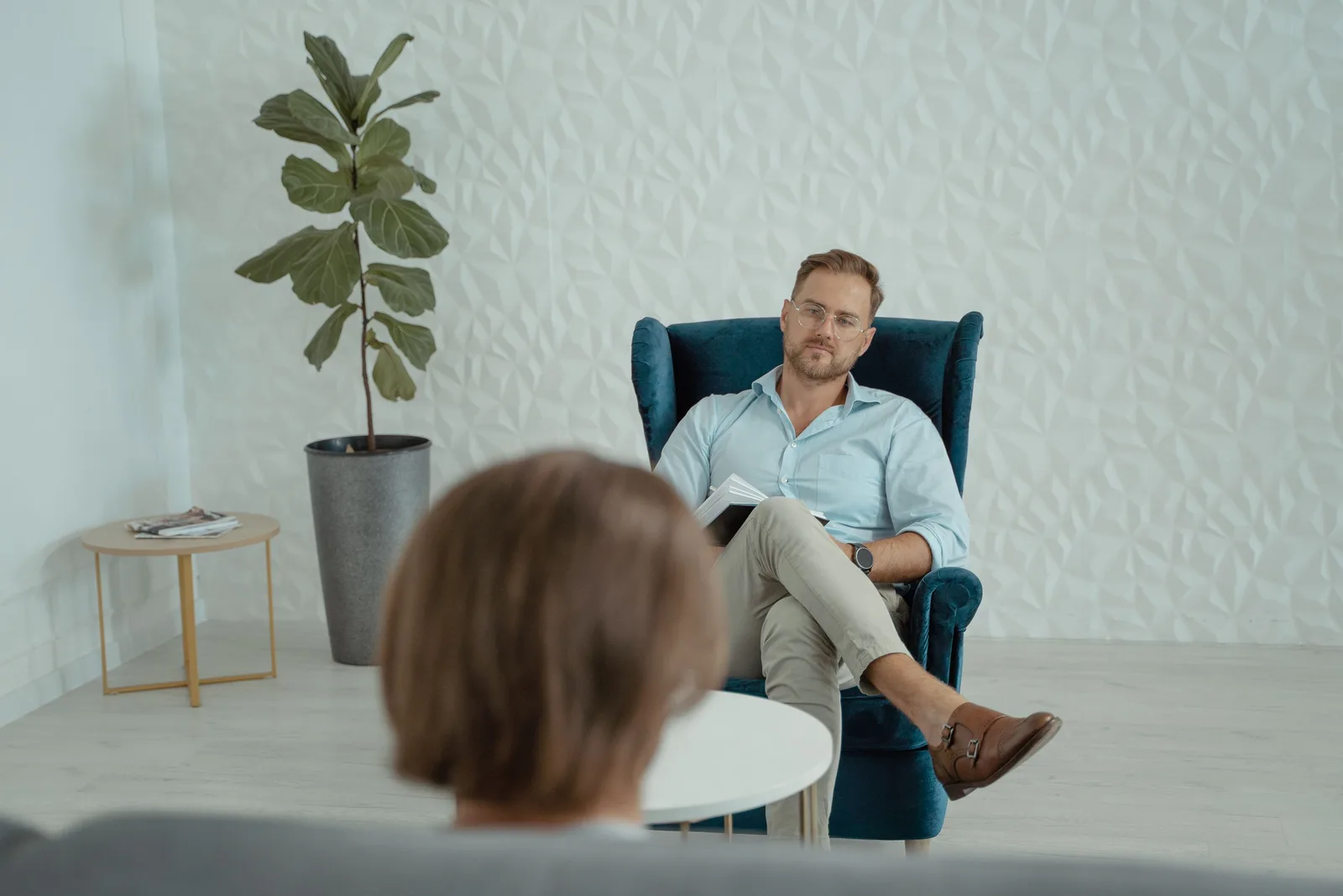 Psychologist seated in an armchair in a calm, bright counselling room with plants. Photo by Tima Miroshnichenko on Pexels