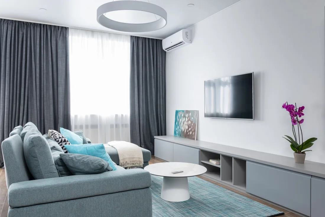 Modern living room with a split air conditioner above the television in Singapore. Photo by Max Vakhtbovych on Pexels