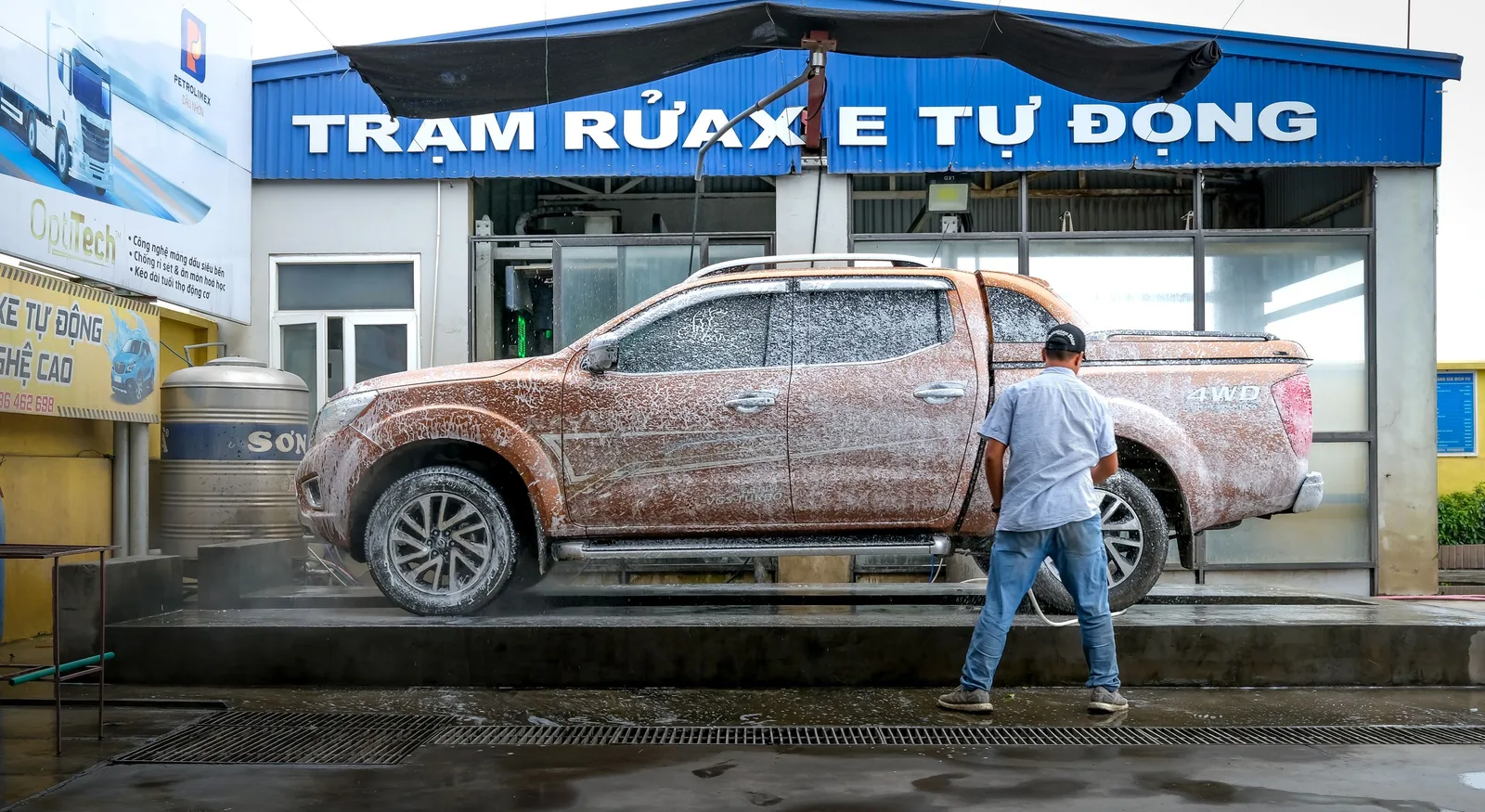 A pickup truck being cleaned at a modern automated car wash facility with a worker present. Photo by Quang Nguyen Vinh on Pexels