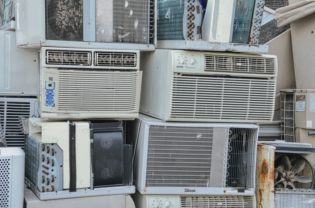 A pile of old window air conditioners awaits recycling, illustrating electronic waste issues. Photo by Tom Fisk on Pexels