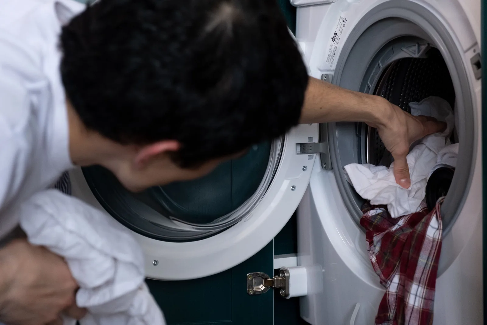 Technician reaching inside a washing machine drum to repair it. Photo by cottonbro studio on Pexels