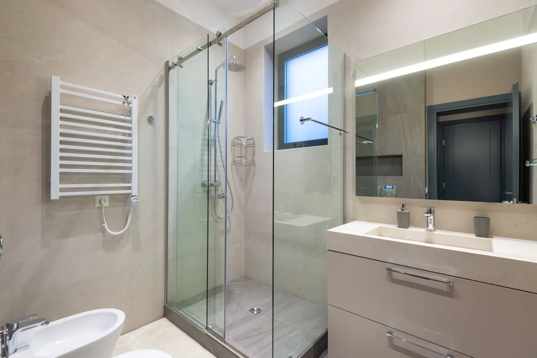 Shower cabin with glass walls near mirror hanging on wall above sink in modern minimalist styled bathroom. Photo by Max Vakhtbovych on Pexels