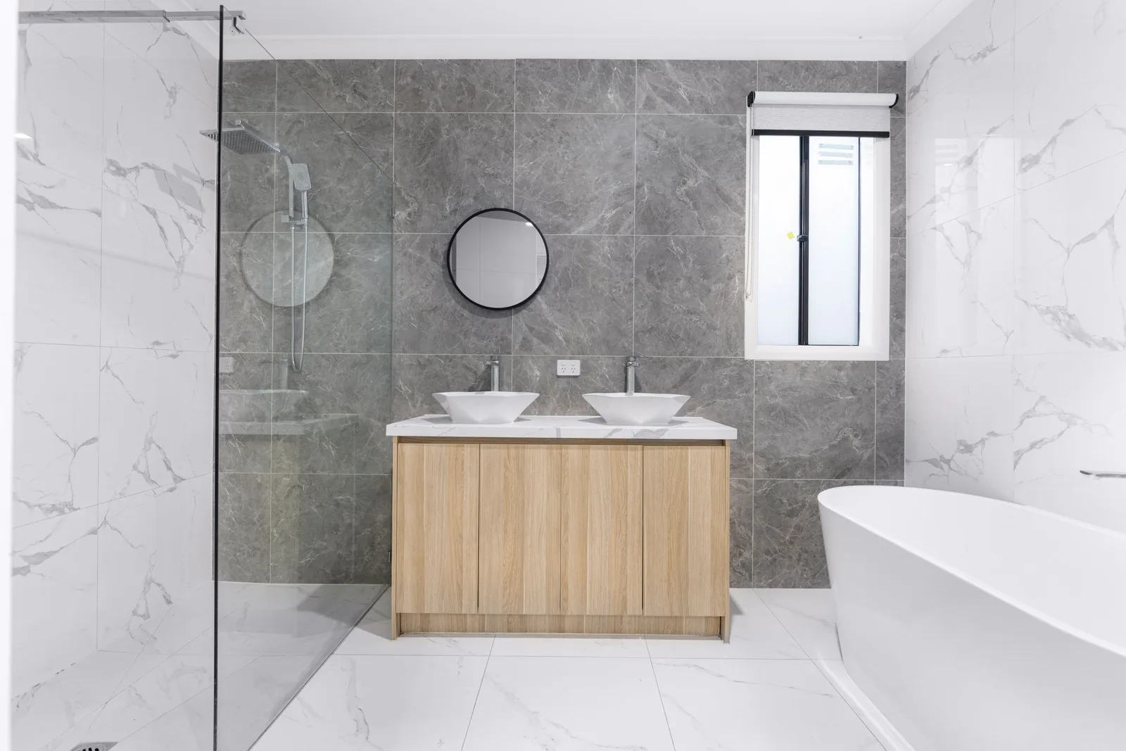 A sleek and stylish modern bathroom with minimalist design, featuring dual washbasins, marble tiles, and a glass shower enclosure. Photo by Arshad Khan on Pexels