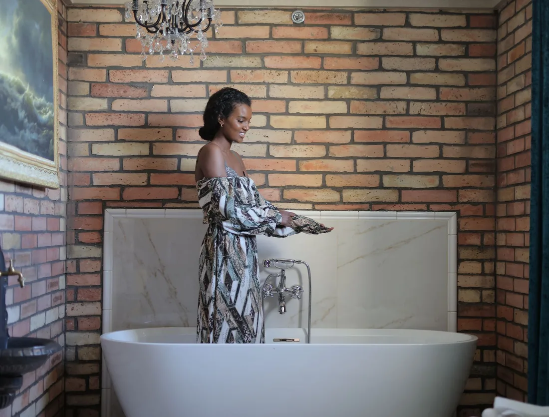 A stylish woman enjoying a tranquil moment in a chic brick-walled bathroom. Photo by Andrea Piacquadio on Pexels