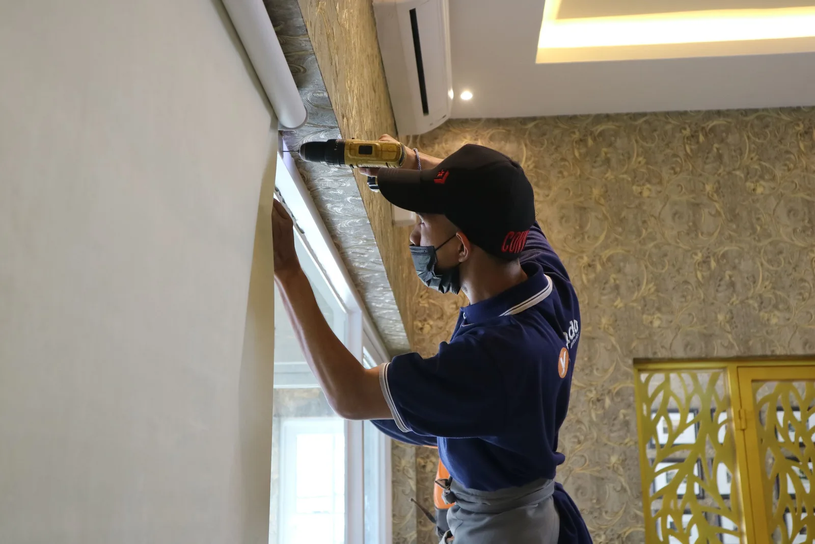 A worker using a drill to install window blinds in an indoor setting. Photo by gorden murahmalang on Pexels