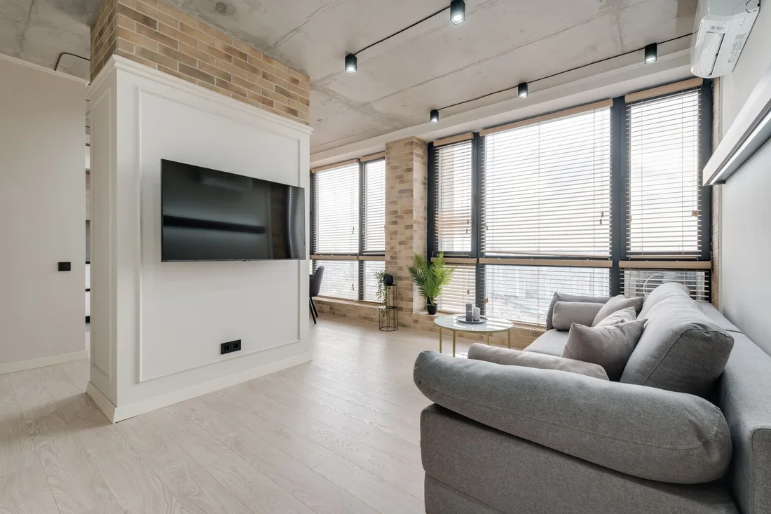 Modern living room with grey sofa and horizontal blinds on large windows. Photo by Max Vakhtbovych on Pexels