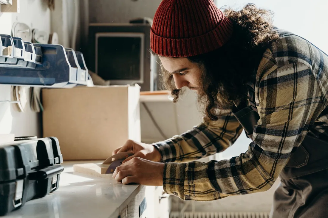 Focused young male carpenter sanding wood at a workbench indoors. Photo by cottonbro studio on Pexels