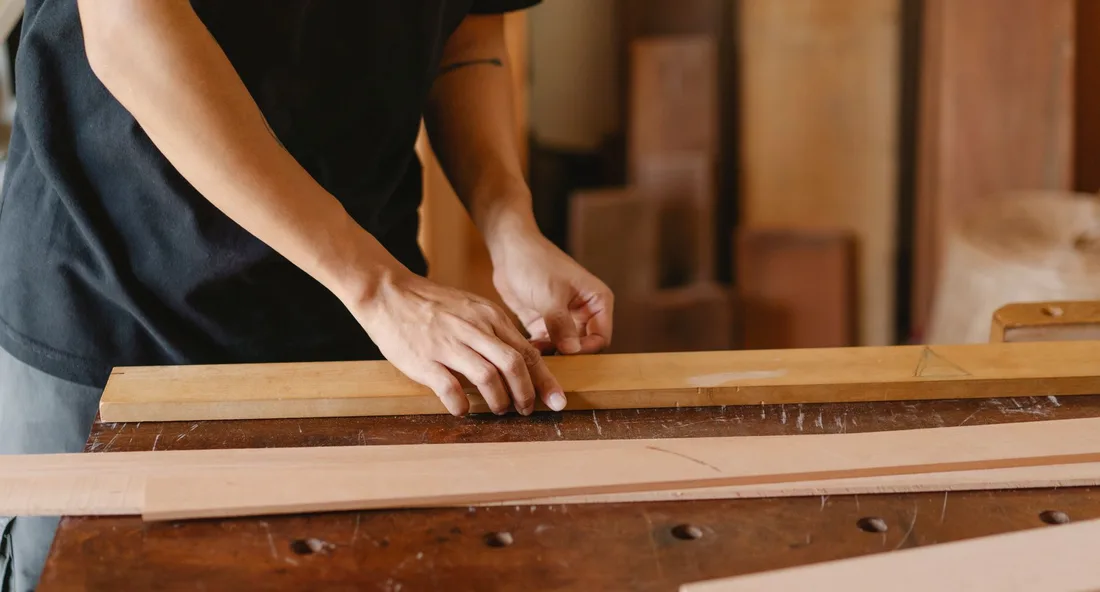 Crop anonymous artisan working with wooden planks in professional carpenter studio in daytime. Photo by Ono  Kosuki on Pexels