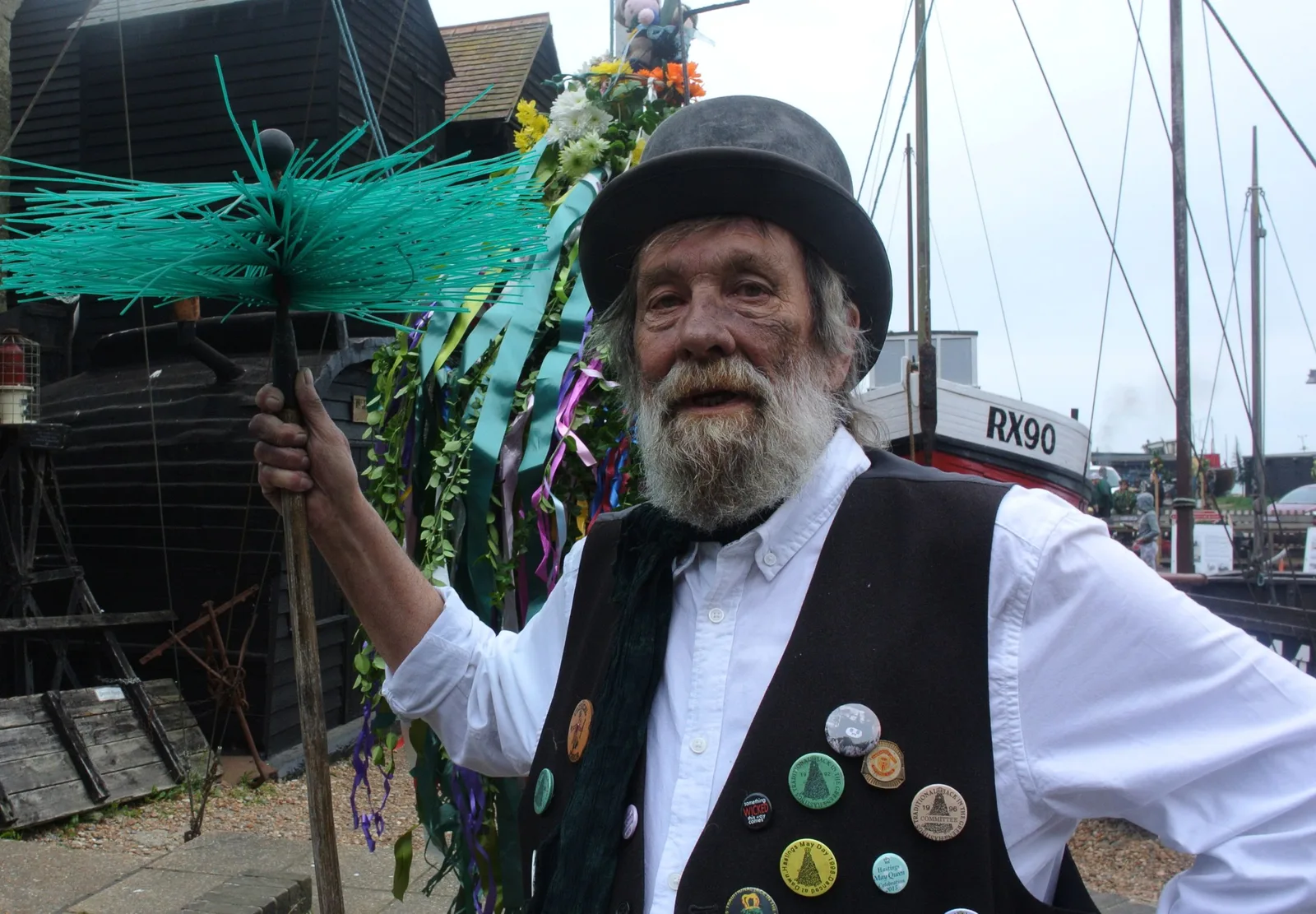 Elderly man in traditional costume participating in outdoor festival with vibrant decorations and boats. Photo by Nick on Pexels
