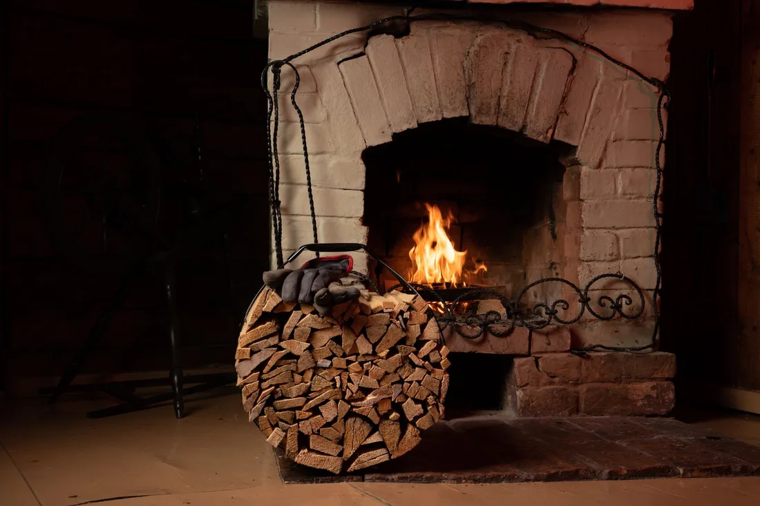 Brick fireplace with a burning fire and a stack of firewood beside it in the UK. Photo by Vilnis Husko on Pexels