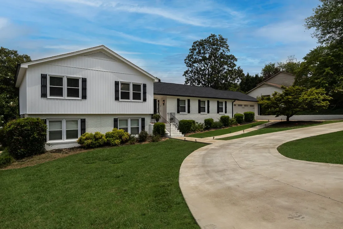 Suburban home with a smooth concrete driveway curving through a green lawn. Photo by Arshad Khan on Pexels