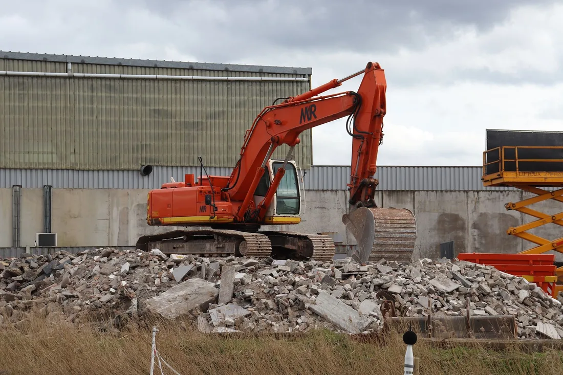 Orange excavator on a pile of broken concrete at a cleared demolition site. Photo by Jef K on Pexels