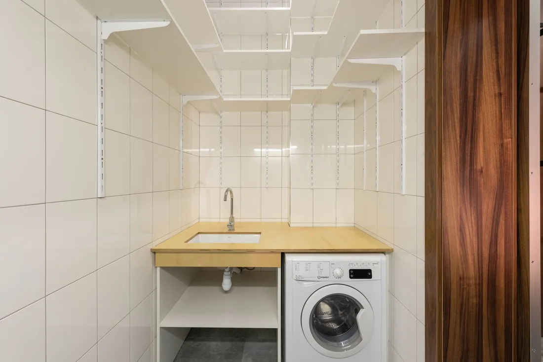 Clean white laundry room with a front-loading washing machine and sink counter. Photo by Max Vakhtbovych on Pexels