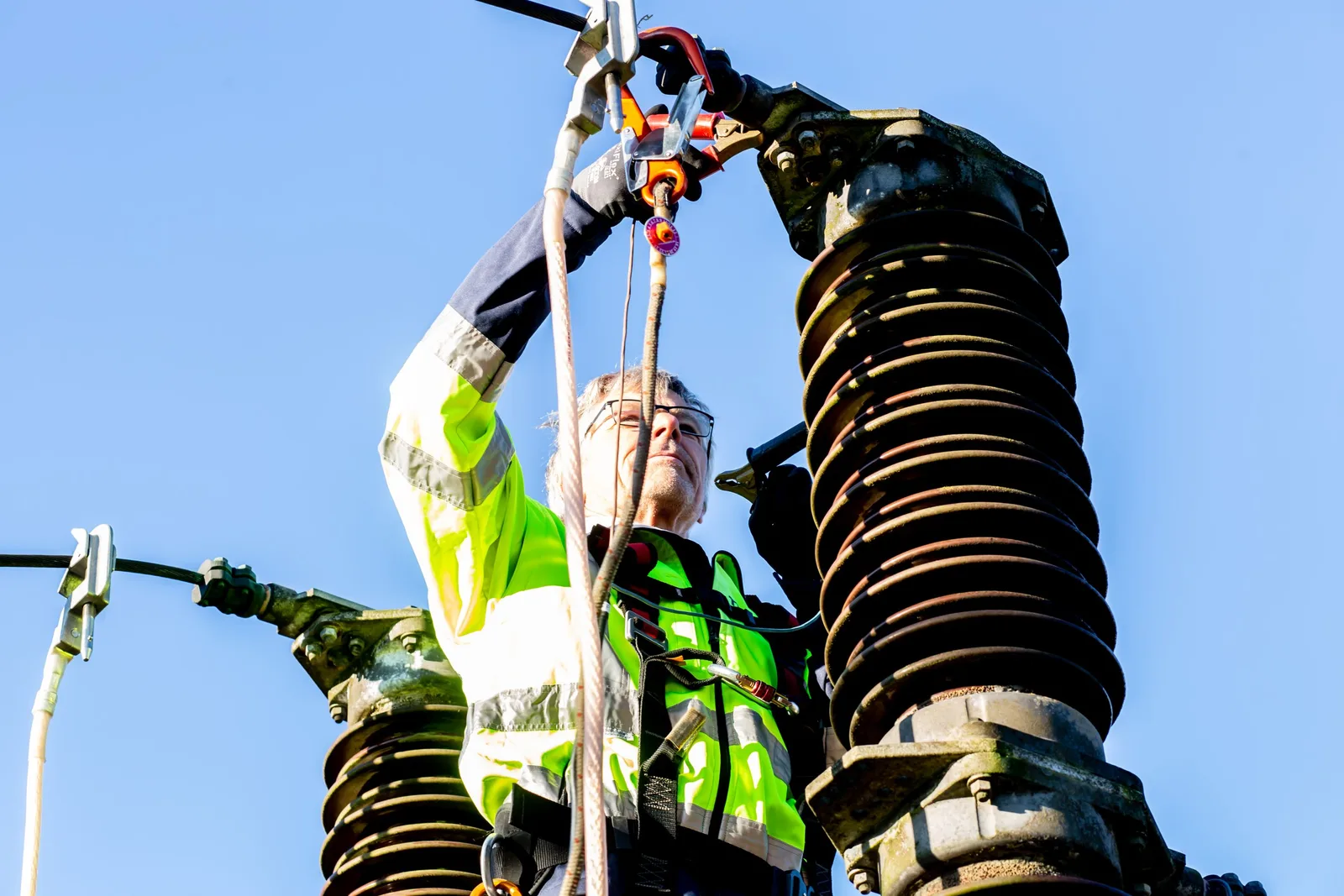 Safety-conscious worker inspecting high-voltage power structures on a clear day. Photo by Rene Terp on Pexels