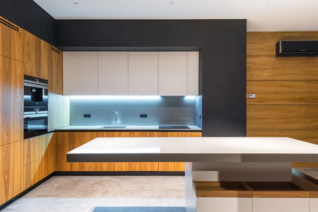 Modern kitchen with warm wood cabinetry and blue LED lighting under the cabinets. Photo by Max Vakhtbovych on Pexels