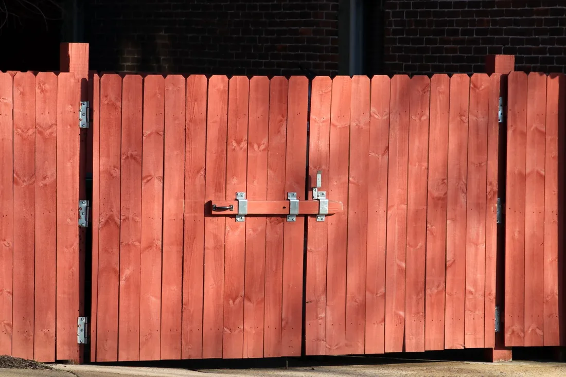 Rustic red wooden fence with a metal latch, ensuring safety and security outdoors. Photo by Gene Samit on Pexels
