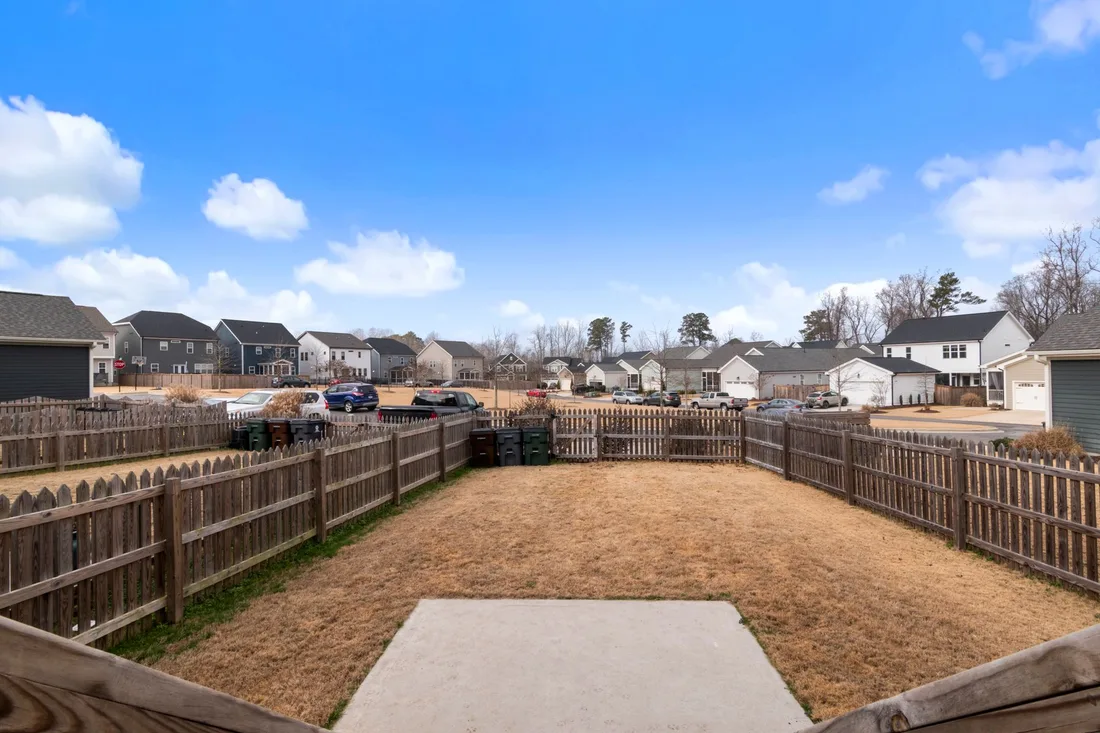 Fenced backyard with new wooden fencing under a bright blue sky. Photo by Curtis Adams on Pexels