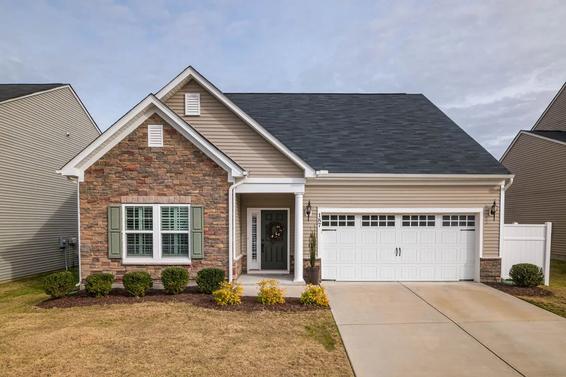 Brick and siding house with a white garage door and a driveway in sunshine. Photo by Curtis Adams on Pexels