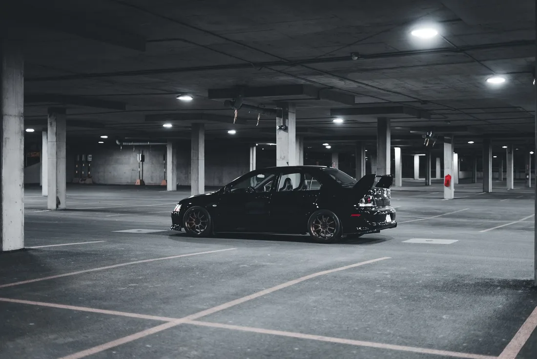 Black Mitsubishi Lancer Evolution parked in a dimly lit urban parking garage. Photo by Erik Mclean on Pexels