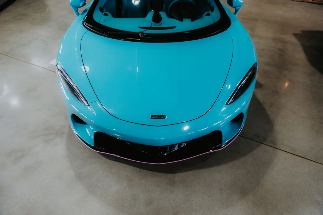 Turquoise sports car parked on a smooth polished garage floor. Photo by Luke Miller on Pexels