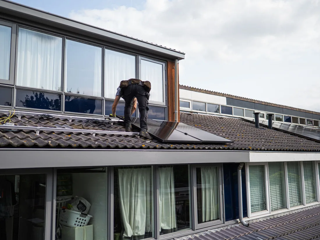 Technician working on installing solar panels on a residential rooftop during the day. Photo by Stefan de Vries on Pexels