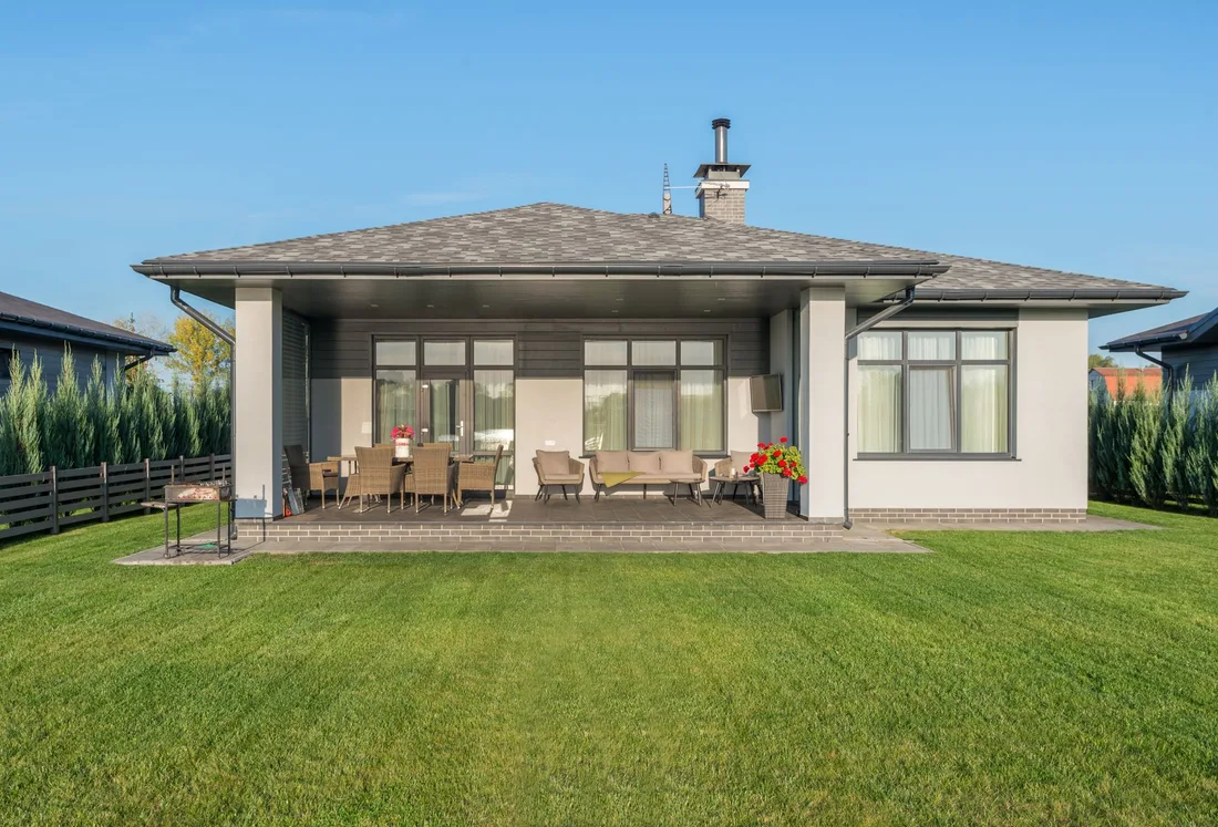 Single-story house with a covered back patio and large green lawn. Photo by Max Vakhtbovych on Pexels