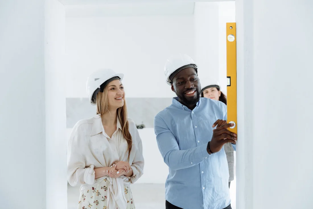 Homeowner and contractor in a hard hat discussing work in a home. Photo by Thirdman on Pexels