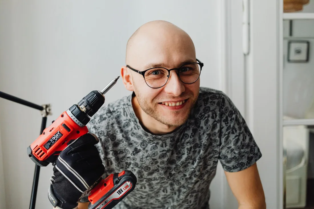 Smiling handyman holding a cordless drill. Photo by https://kaboompics.com/ on Pexels