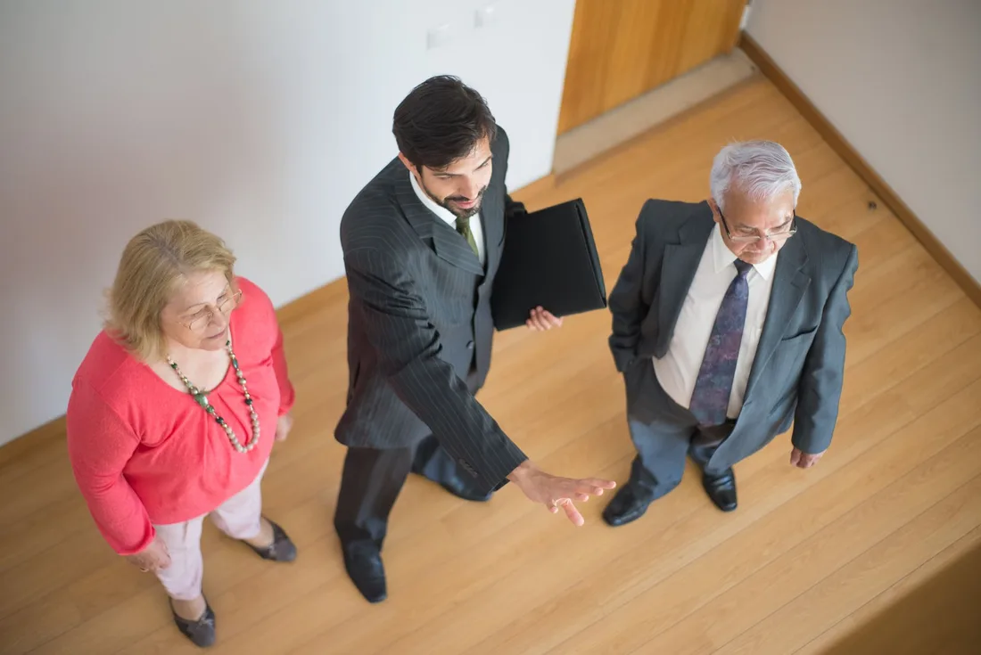 A realtor shows a property to a senior couple in a modern indoor setting. Photo by Kampus Production on Pexels