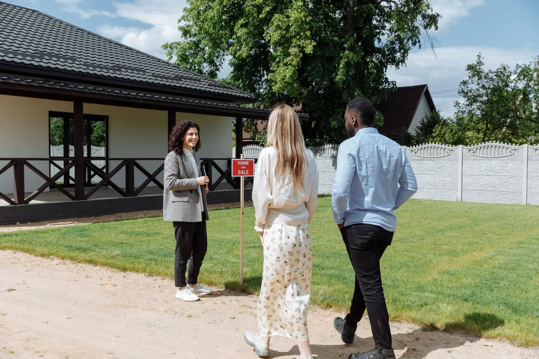 Couple and agent walking toward a house across the lawn on a sunny day. Photo by Thirdman on Pexels
