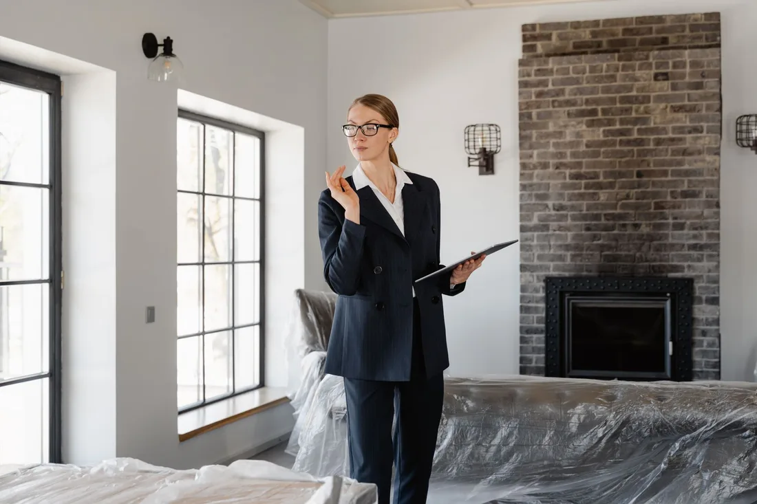 A confident real estate agent inspecting a modern home's interior with fireplace and large windows. Photo by MART  PRODUCTION on Pexels