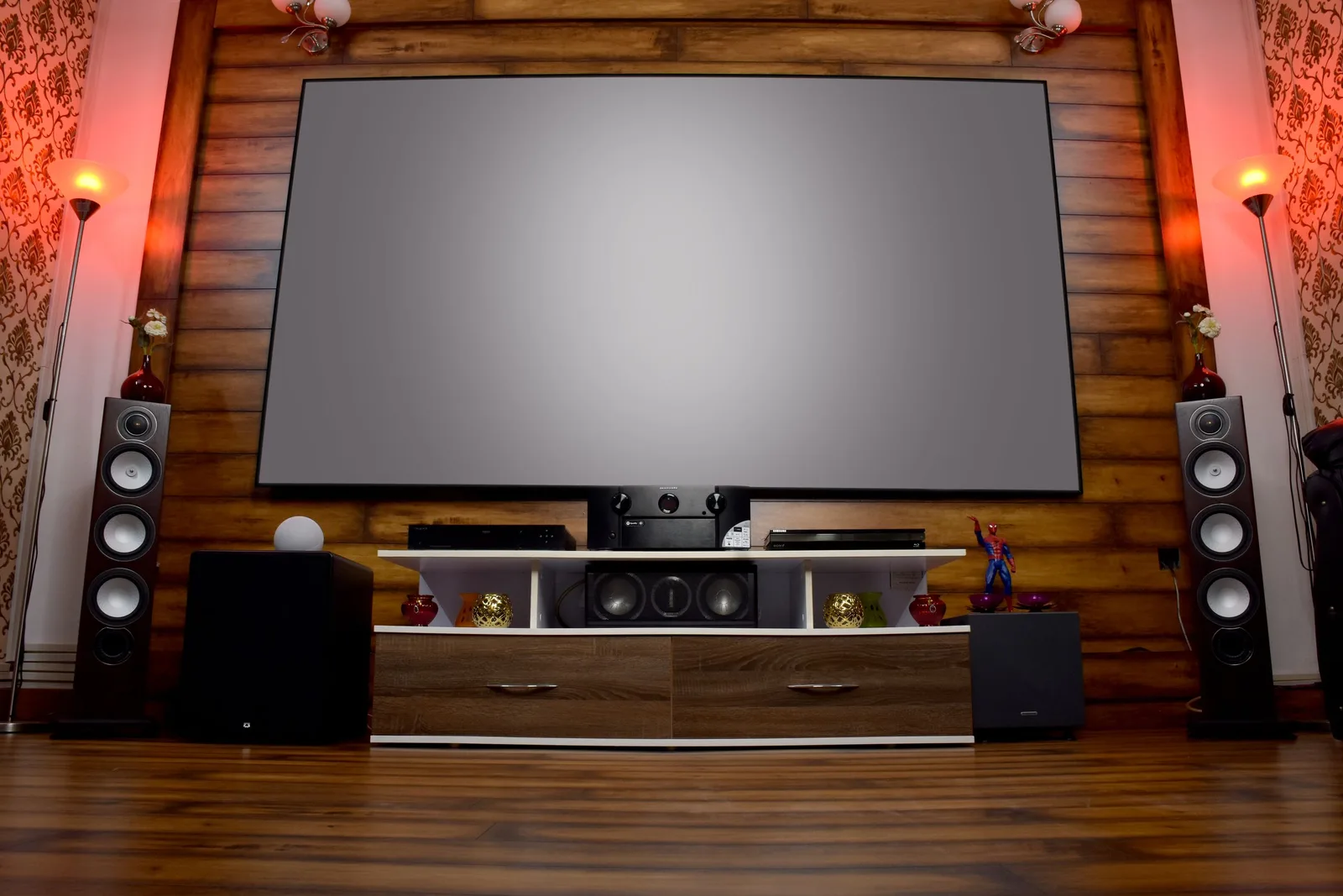 Home theater with large projector screen, floor-standing speakers and wood wall. Photo by Avinash Kumar on Pexels