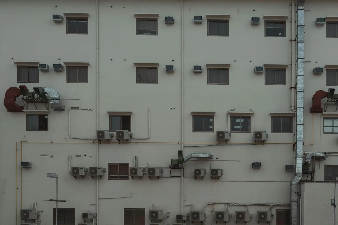 A building facade covered with air conditioning units and ducts illustrating urban architecture. Photo by Austin Briones on Pexels