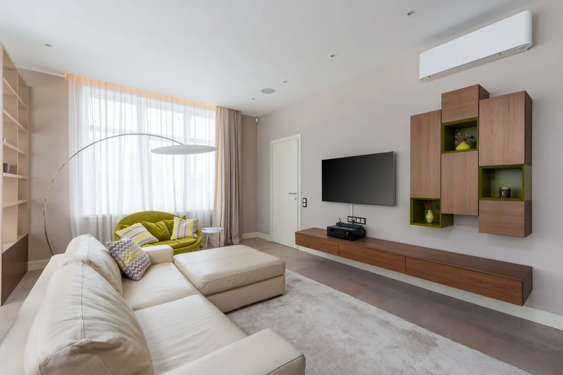 Bright modern living room with a wall-mounted split air conditioner above a sofa and window. Photo by Max Vakhtbovych on Pexels