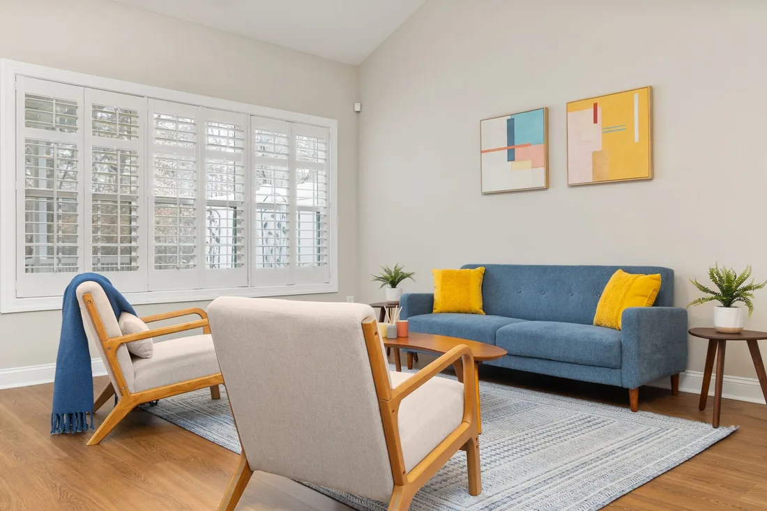Bright living room with blue sofa, armchairs and framed art. Photo by Curtis Adams on Pexels