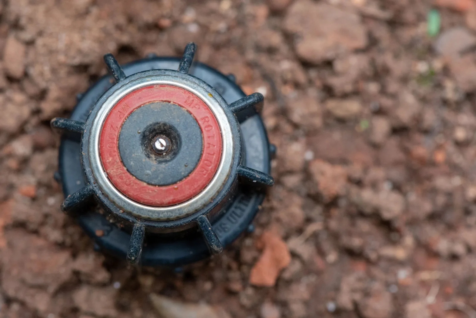 Close-up image of a garden sprinkler head embedded in soil, ideal for landscaping themes. Photo by Malcoln Oliveira on Pexels