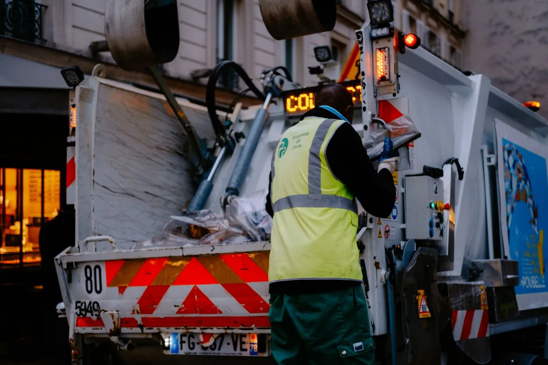A garbage collector works on a city street, managing waste collection at dusk. Photo by Mathias Reding on Pexels