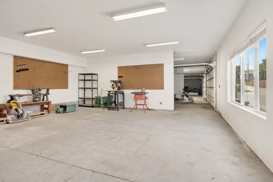 Bright empty garage space with white walls, windows and tidy open floor. Photo by hi room on Pexels