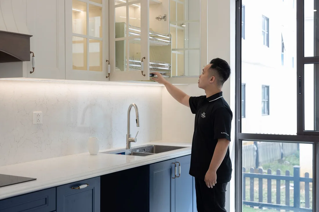 A person organizing a modern kitchen cabinet with elegant design and bright lighting. Photo by HONG SON on Pexels