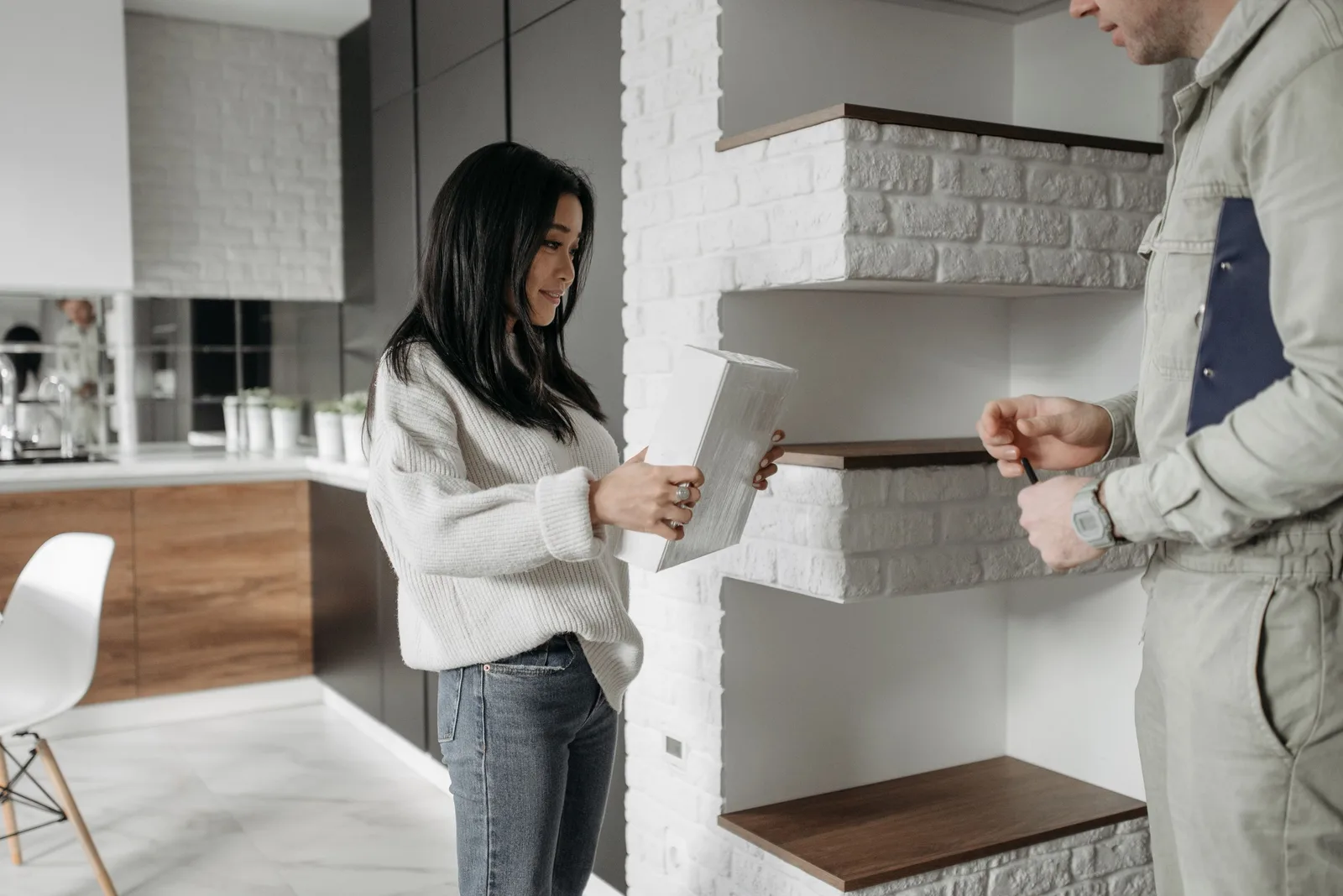 Asian woman unpacks a package while talking to a handyman in a stylish kitchen. Photo by Pavel Danilyuk on Pexels